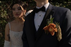 A formal wedding portrait against a dark background with elegant attire and floral details.