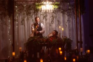 Warm candlelit wedding reception venue with forest-themed decor and hanging lights.