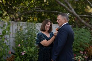 A couple shares a romantic moment outdoors during a wedding celebration in a garden setting.
