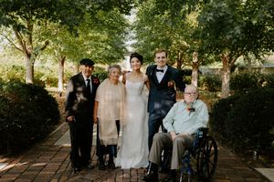 Wedding group photo taken on a tree-lined brick pathway.
