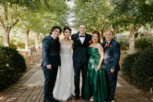 Wedding party in formal attire posing outdoors with emerald green and black color scheme.