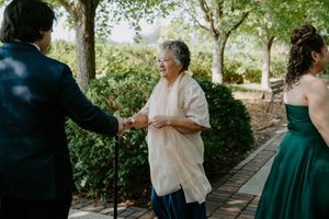 Wedding party members share joyful moments and laughter in an outdoor garden setting.