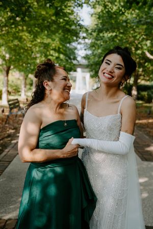 Bridesmaids in emerald green dresses share a candid moment with the bride in white.