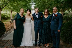 Wedding party poses together on a tree-lined pathway wearing formal attire.