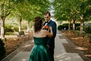 Wedding party members walk together along a scenic garden path.