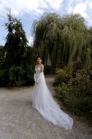 Bridal portrait in garden setting with dramatic train flowing behind white wedding gown.