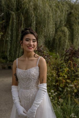 A close-up view of a wedding dress with intricate beaded bodice and white elbow-length gloves.