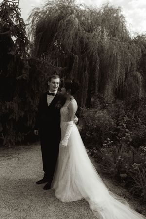 A black and white wedding portrait under a dramatic weeping willow tree.
