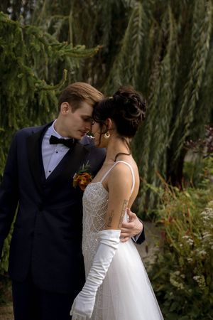 A romantic moment between newlyweds under weeping willow trees.