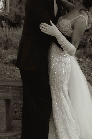 Close-up of an ornate beaded wedding dress bodice with white gloves.