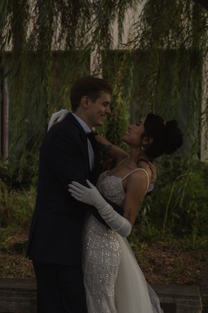 A couple sharing an intimate moment under weeping willow trees at dusk.
