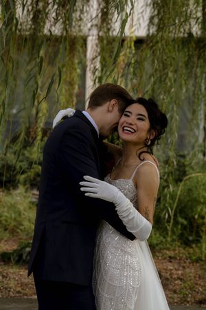 Newlyweds share a romantic moment under a weeping willow tree during their wedding photoshoot.