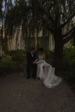 A couple dancing together under willow trees at twilight in a garden setting.