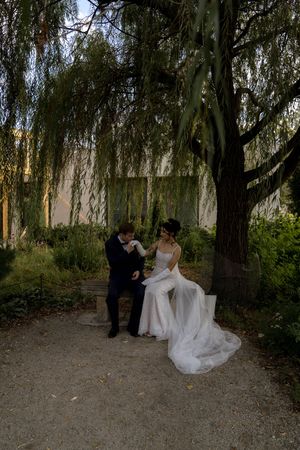 Wedding couple poses for romantic portraits in a garden setting with dramatic weeping willow trees.