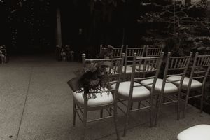 Empty wooden chairs arranged for outdoor wedding ceremony with soft lighting.