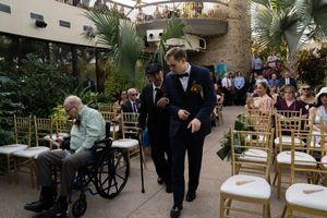 Wedding guests walking through an outdoor venue with tent covering and stone walls.