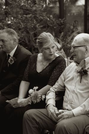 Guests seated together in formal attire at an outdoor event, captured in black and white.