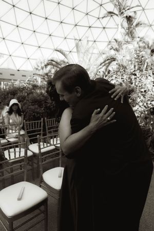 An intimate embrace photographed under a modern glass dome structure at an event.