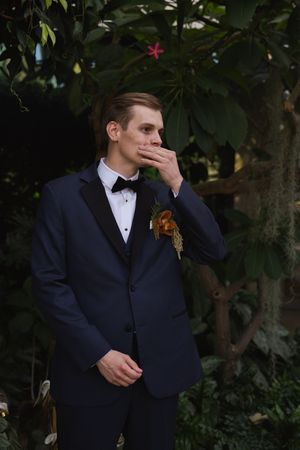A groom in navy suit and bowtie showing emotion during wedding portraits.