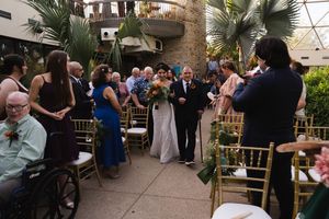 Wedding ceremony venue with tropical landscaping and rows of gold chairs.