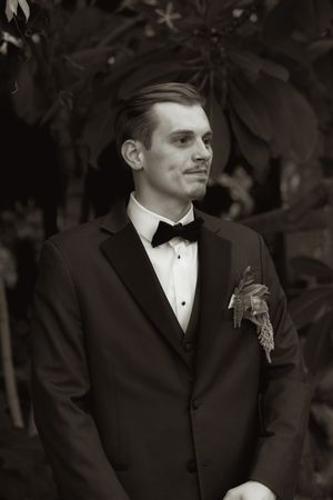 Black and white portrait of a groom in classic tuxedo with boutonniere.