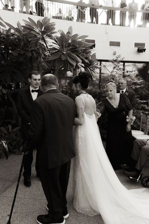 Black and white photo of a wedding ceremony processional in an elegant courtyard setting.