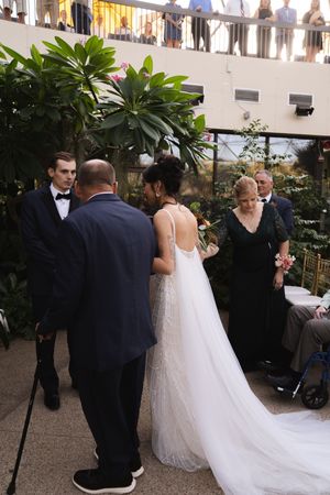 Wedding ceremony processional with flowing white dress train in a tropical courtyard setting.