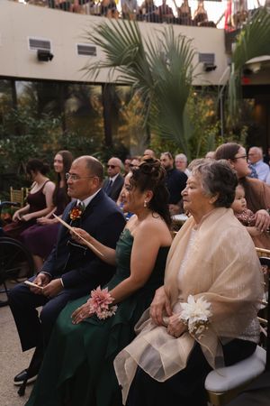 Guests watch attentively during an indoor garden wedding ceremony.