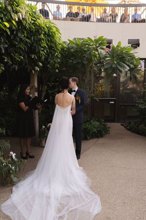A wedding ceremony moment under hanging lights in a lush garden setting.