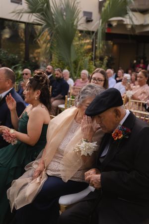 Wedding attendees seated in rows share laughter during an indoor garden ceremony.