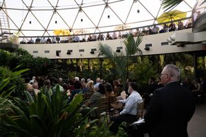 Panoramic view of a wedding ceremony space with tropical plants under a geometric glass ceiling.