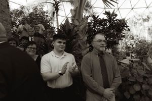 Panoramic view of guests seated for a wedding ceremony in a greenhouse setting.