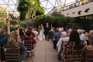 Guests gather for an indoor garden wedding ceremony beneath a modern glass geodesic dome structure.