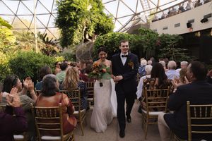 Wedding celebration in a greenhouse venue with natural light streaming through geometric glass panels.