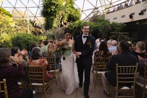 Elegant wedding ceremony setup in a botanical garden conservatory with gold chiavari chairs.