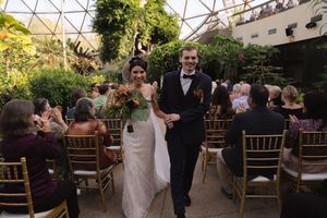 Wedding guests seated in an indoor garden venue with geometric glass ceiling and lush greenery.