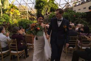 Wedding celebration in greenhouse venue with dramatic geometric glass ceiling and natural decor.