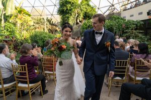 Wedding celebration in a greenhouse conservatory surrounded by tropical plants.