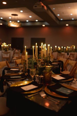 Elegant wedding reception table with black linens, gold candles, and formal place settings.