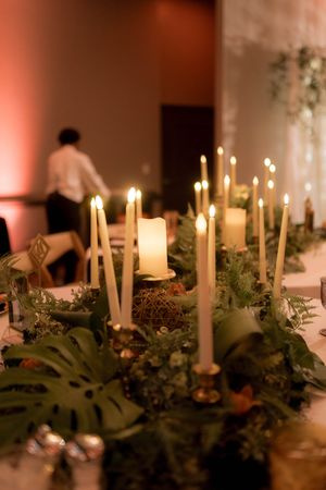Romantic wedding centerpiece with glowing candles and lush greenery on table.