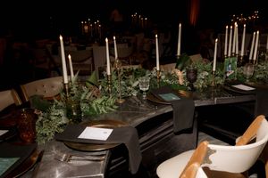 Modern wedding reception table with white candles and greenery runner.