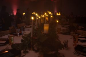 Atmospheric wedding table setting with warm candlelight and dark ambient lighting.