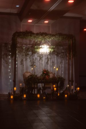Dimly lit wedding venue decorated with hanging lights and floral arrangements creating a romantic ambiance.