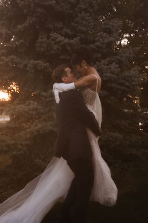 Newlyweds dancing together outdoors during golden hour with flowing white dress movement.