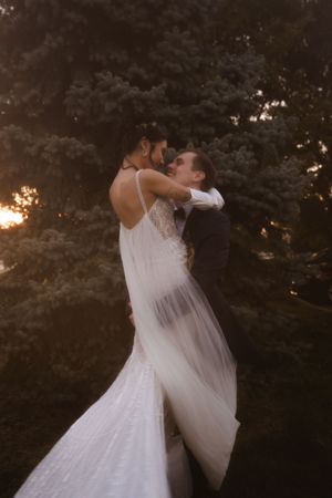 Wedding couple embracing in a dramatic dance pose during sunset.