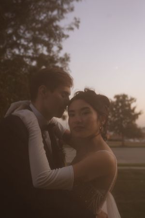A romantic sunset portrait of newlyweds embracing in an outdoor setting.