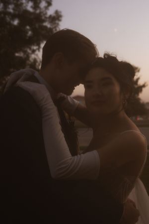 An intimate moment between a couple in wedding attire during golden hour.