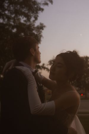 A tender embrace between newlyweds captured in soft evening light.