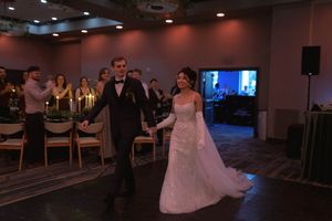 A wedding couple dancing in a dimly lit reception hall with guests watching.