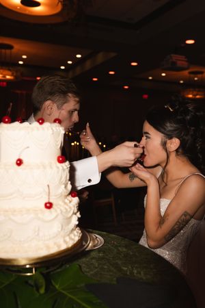 A playful cake-feeding moment between newlyweds at their reception.